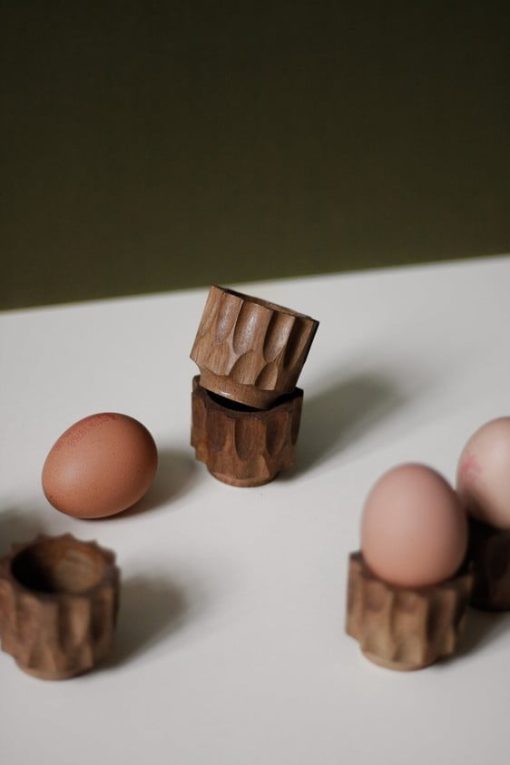 Hand carved egg cups stacked next to hard boiled eggs.